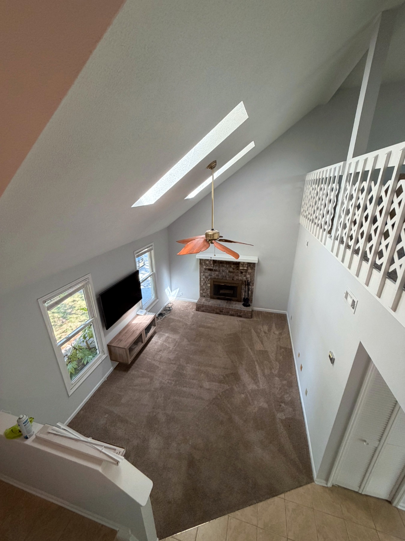 Vaulted two-story living room with soft gray walls, white trim, and a brick fireplace