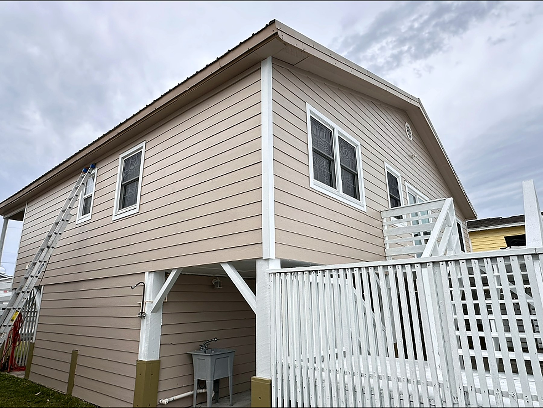 Raised beach house repainted in warm greige with crisp white trim and posts