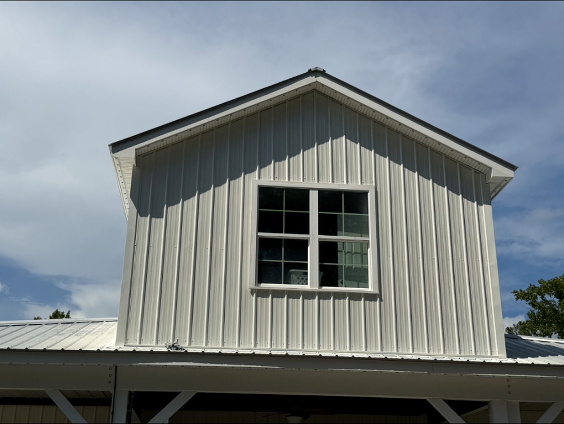 Two-story gable with crisp white vertical siding and a bright window under a coastal sky
