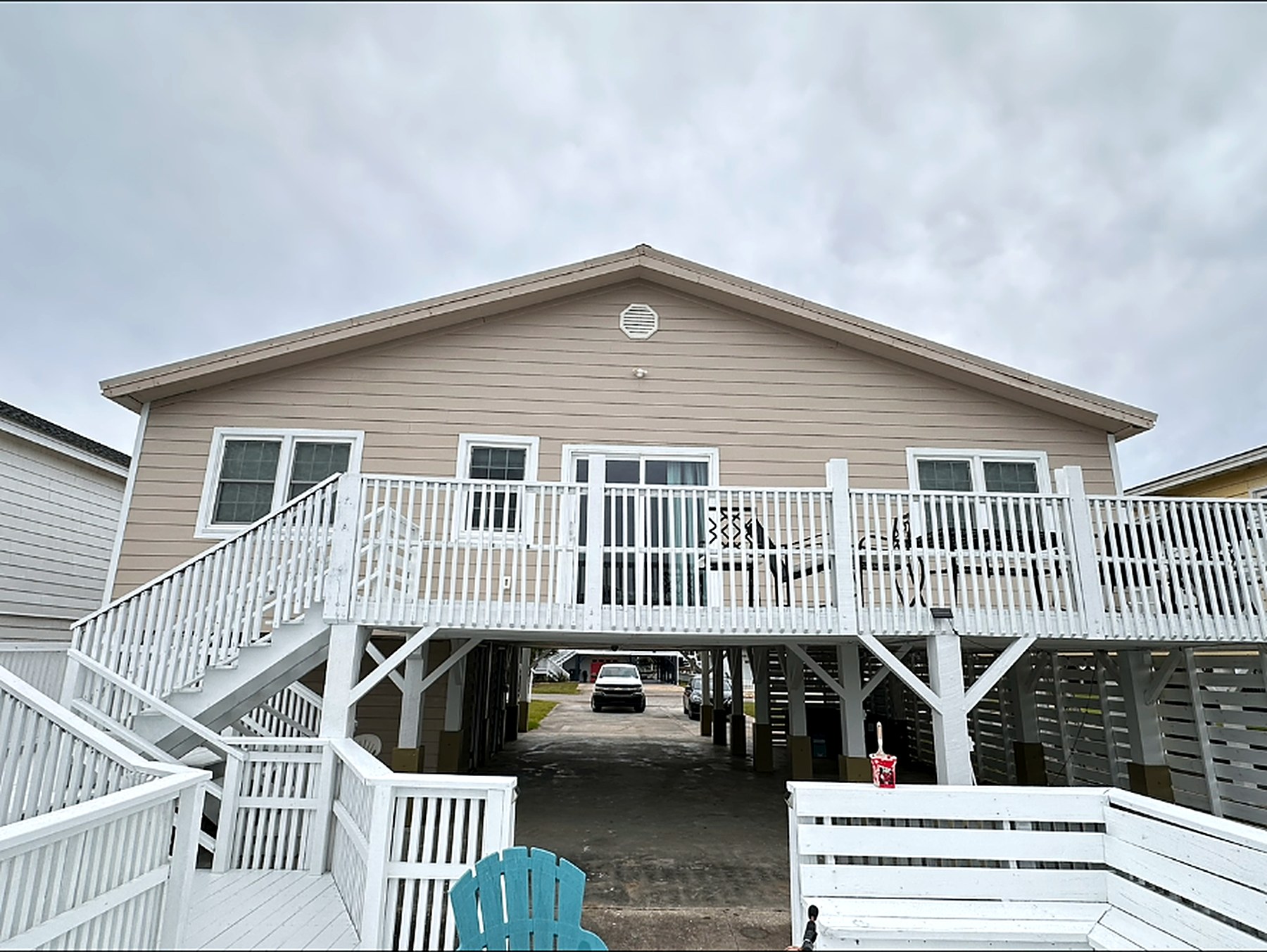 Rear elevation of a raised beach house with freshly painted siding and white deck railings