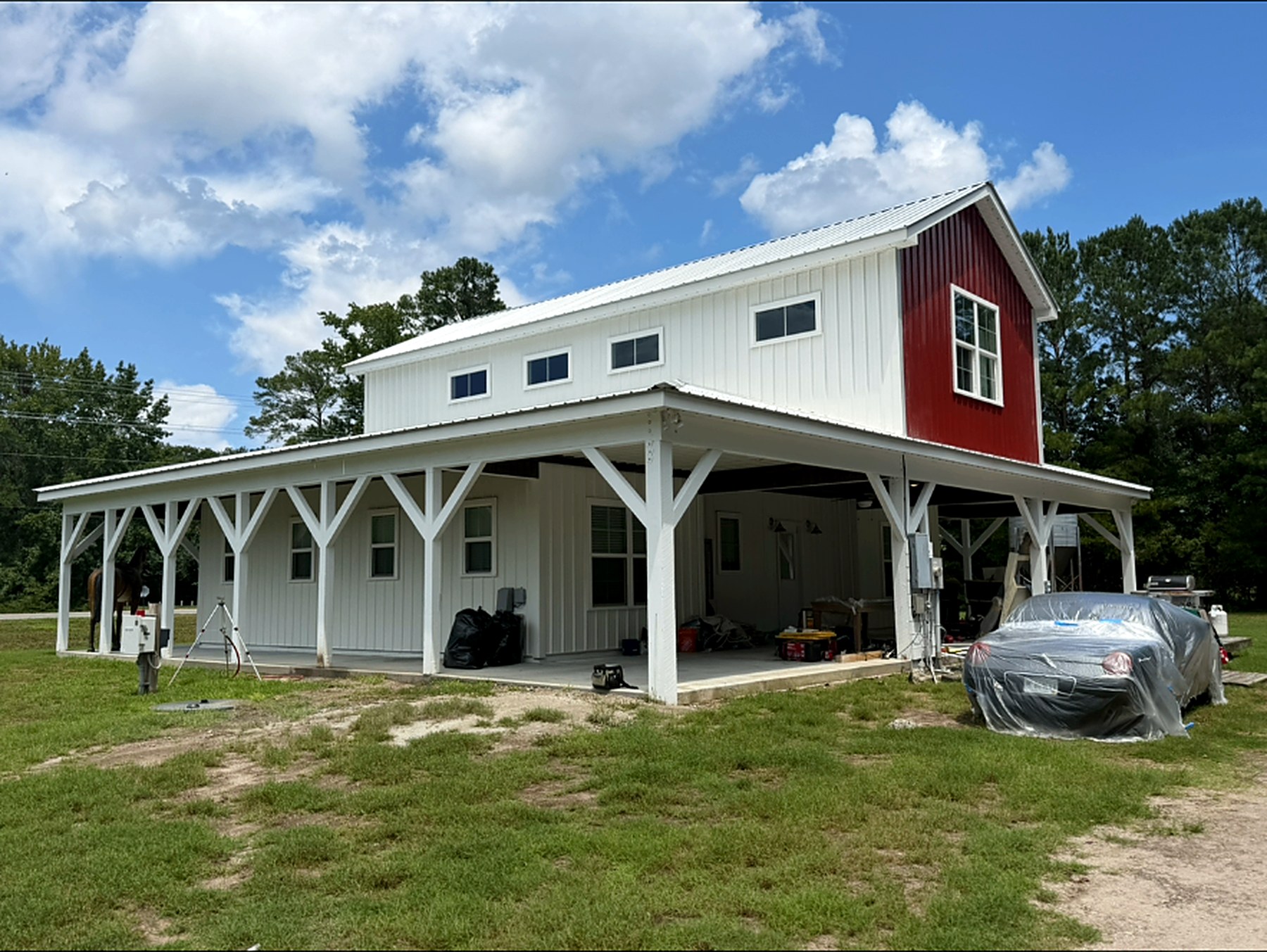 Two-story white farmhouse with wrap-around porch and red accent siding after a full exterior repaint