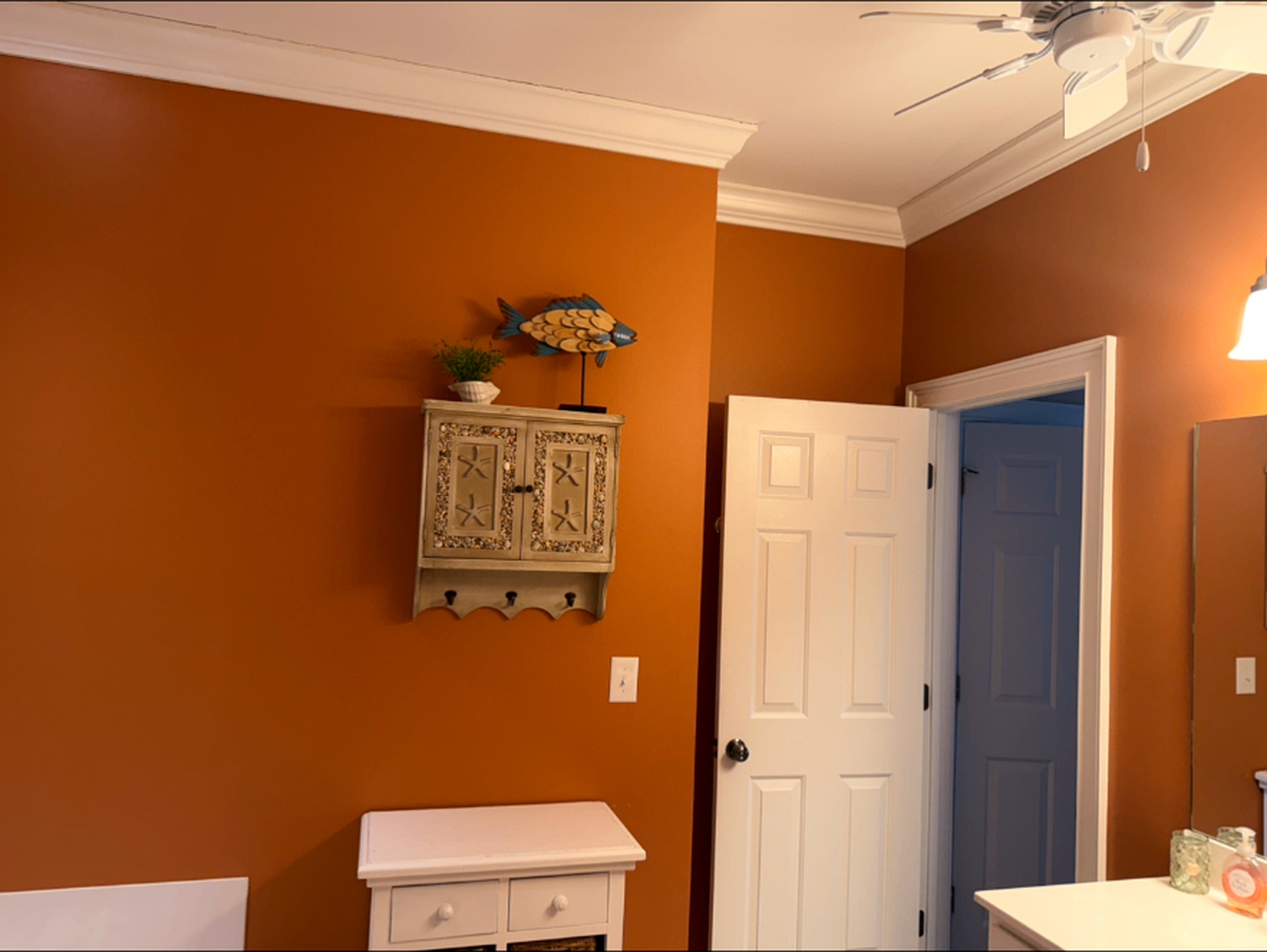 Interior room with warm terracotta walls, crisp white crown molding, trim, and doors